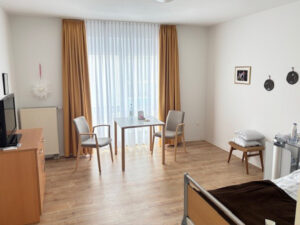 Aufenthalt im Einbettzimmer mit bodentiefen Fenstern und einem Tisch mit zwei Stühlen