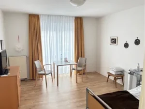 Aufenthalt im Einbettzimmer mit bodentiefen Fenstern und einem Tisch mit zwei Stühlen
